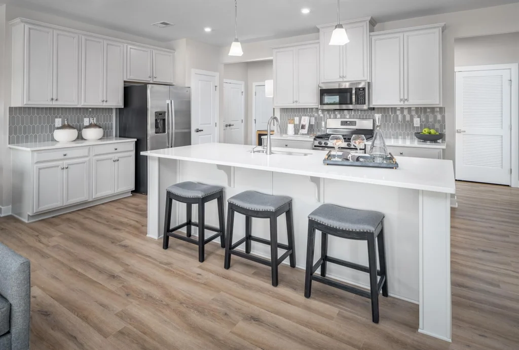 Open kitchen with a large white island, gray bar stools and stainless-steel appliances